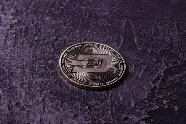 Una criptomoneda en un fondo oscuro. Descubre las predicciones del precio del Dash.