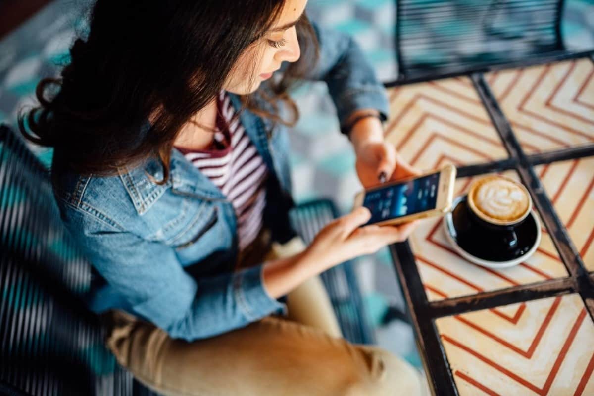Una joven revisa tendencias de mercado desde su celular y analiza cómo invertir en divisas.