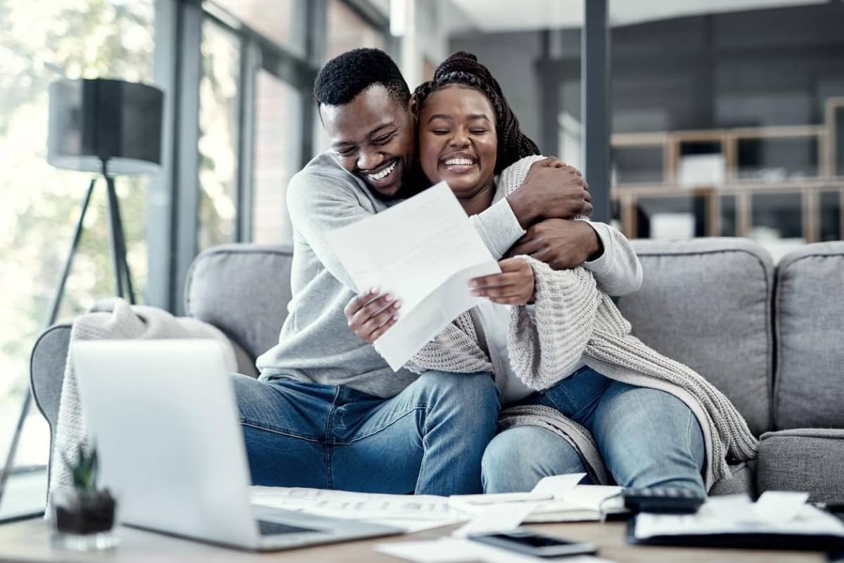 Una pareja se abraza, revisa documentos de balances y disfruta su libertad financiera.