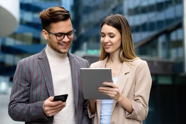 Dos personas consultan en una tablet cómo comprar acciones de una empresa.