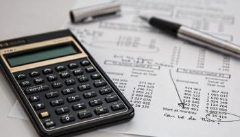 Calculadora y papeles que simbolizan cómo armar un portafolio de inversiones.