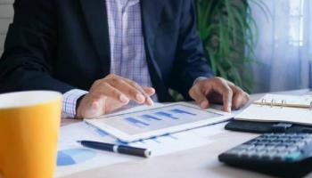 Hombre vestido con traje viendo en su tablet algunos instrumentos financieros y ejemplos.