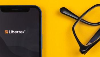 Logo de la mejor plataforma de trading Libertex en un celular sobre una mesa