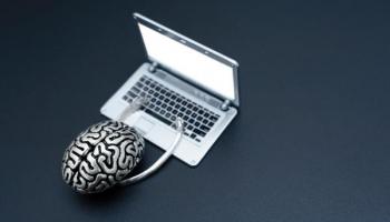 Cerebro representando la mentalidad correcta en el trading usando un computador frente a un fondo gris oscuro